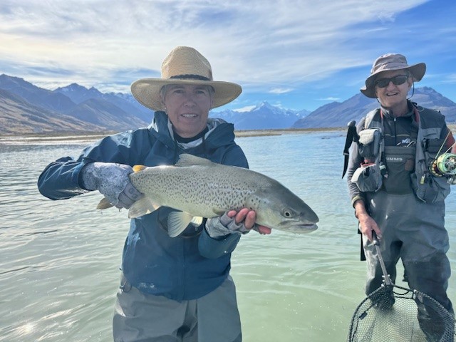 Another trout caught with a happy guide in the background.